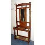 A stained wood hall stand, the shaped foliate carved top decorated with spindle supports,