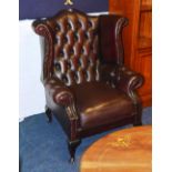 A red Chesterfield wing back buttonback armchair, with cushion arm rests, raised on cabriole