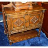 A Jacobean style carved oak cabinet, with two panelled doors decorated with carved foliate lozenges,