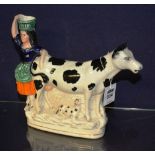 A 19th century Staffordshire cow creamer, modelled with glazed female figure and recumbent calf,