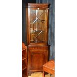 A reproduction mahogany corner cabinet, with glazed astragal door enclosing shelved interior,