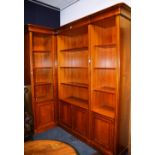 A large modern open bookcase, in three sections, with shelved interior above four panelled doors,