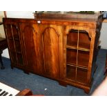 A mahogany bookcase, with two panelled doors flanked by a glazed door enclosing shelved interior,