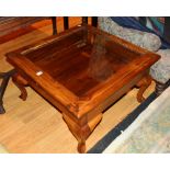 A modern hardwood coffee table, of square form with glazed hinged top, raised on cabriole supports,