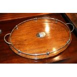 An oak serving tray, of oval form, with plated gallery and mount, raised on four plated bun feet,