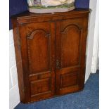 A Georgian oak corner cupboard, with two panelled doors enclosing fitted shelves,