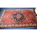 A Persian Tafresh rug, the central medallion over red ground with bird and floral decoration,