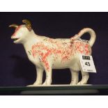 A 19th century Staffordshire cow creamer, with orange and black sponged decoration to body,