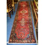 A fine Persian Mehraban runner, with medallions and floral design over red ground with triple