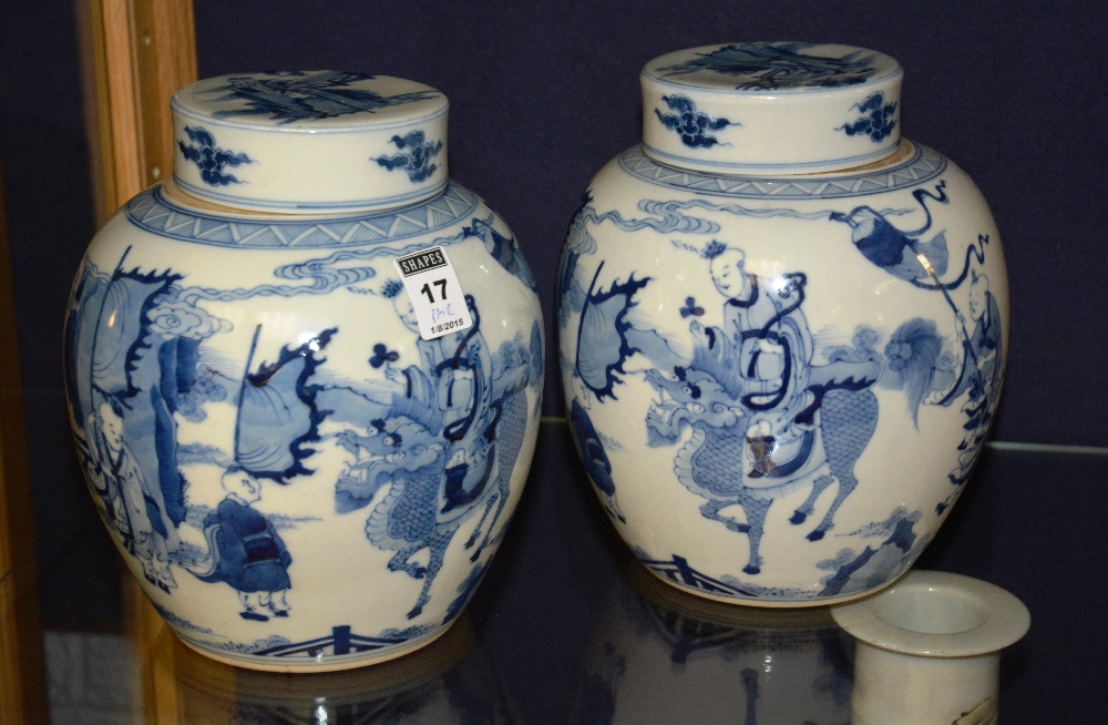 A pair of Chinese ginger jars and covers, with blue decorated figures in foliage, on white ground,