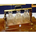 An oak Tantalus, with plated mounts, enclosing three cut glass decanters and stoppers,