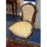 A late Victorian mahogany nursing chair, upholstered in cream floral fabric,