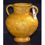 A yellow glazed vase, of bellied form, with twin loop handles, raised on foot,