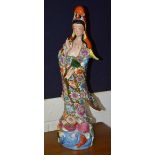 A Chinese figure of Guanyin wearing a floral decorated gown of rich colours, decorated with posies