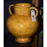 A yellow glazed vase, of bellied form, with twin loop handles, raised on foot,