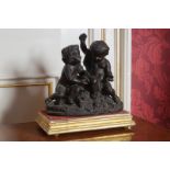 NINETEENTH-CENTURY BRONZED CHERUB GROUP seated on a rocky mound, playing dice, supported on a
