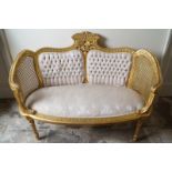 LOUIS XVI STYLE CARVED GILTWOOD AND UPHOLSTERED CANAPÉ with deep buttoned and cane panelled back,