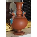 MATCOMBE PARTIAL GLAZED TERRACOTTA VASE of baluster form with mask head scroll handles, raised on