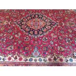 Handmade Persian carpet, circa 1930 on red ground, with central medallion, navy border, and