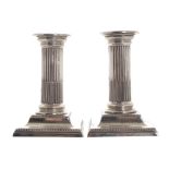 Pair of crested silver candlesticks each with a reeded column and cavetto moulded square base,