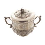 Silver urn and cover with embossed leaf decoration and double scroll handles, below a domed lid with