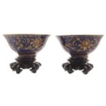 Pair of Chinese Qing period blue enamelled, parcel gilt bowls each raised on a hardwood stand