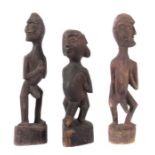 3 Figuren wohl Afrika, Holz geschnitzt, schwarzbraun bemalt, auf Sockel stehende, männliche Figuren,