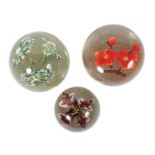 3 Paperweights mit Blüten Mitte 20. Jh., polychrome Blüten, farblos überfangen, in unterschiedlichen