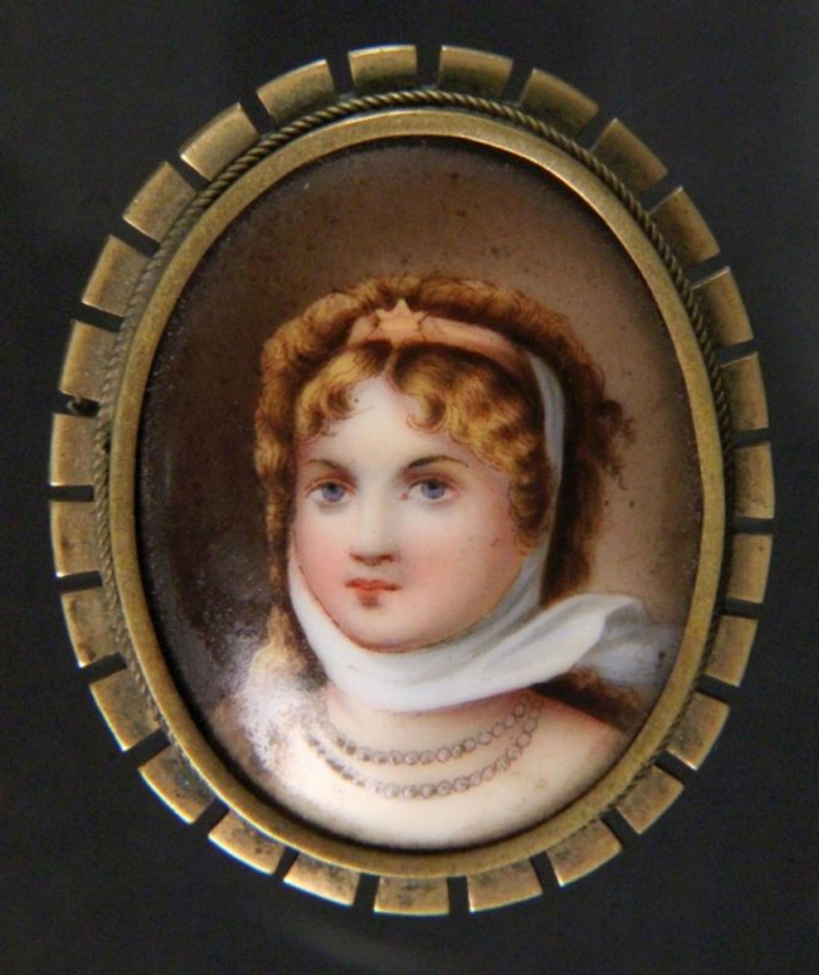 BROSCHE MIT PORZELLANMINIATUROvale Messingfassung mit farbig gemaltem Mädchenportrait auf Porzellan.