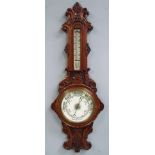 An early 20th century oak cased Aneroid Barometer, the banjo shaped frame carved with leaves and