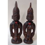 A pair of antique Nigerian carved wooden Yoruba Ibeji figures, male and female, each with beaded