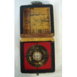 A Chinese brass and black enamel Pocket Compass in a square hinged box externally red lacquered