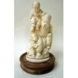 A Japanese ivory Okimono carved figural group depicting a seated robed and bearded old man