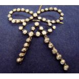 A late 19th/early 20th century diamond set bow brooch in white metal with a yellow metal pin, set