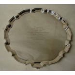 A large George V silver three footed tray, of shaped circular form with raised shaped rim, set on