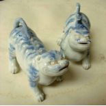 A pair of small Chinese blue and white pottery lion dogs, each crouching and snarling, one with