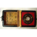 A Chinese brass and black enamel Pocket Compass in a square hinged box externally red lacquered
