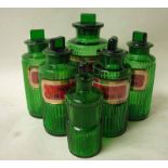 A selection of six green glass pharmaceutical bottles with vertical ribbed boy, five with red and
