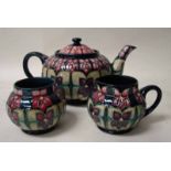 A Walter Moorcroft pottery three piece tea service, tubeline decorated in the Violet design by Sally