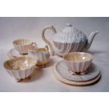 A Belleek porcelain nine-piece tea service for two, of shell form with yellow lustre colouration,