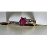 A modern 9ct gold ruby and diamond dress ring of cross over style, the central ruby flanked by two