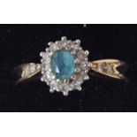 A modern 9ct aquamarine and diamond cluster ring of oval form with a central aquamarine surrounded