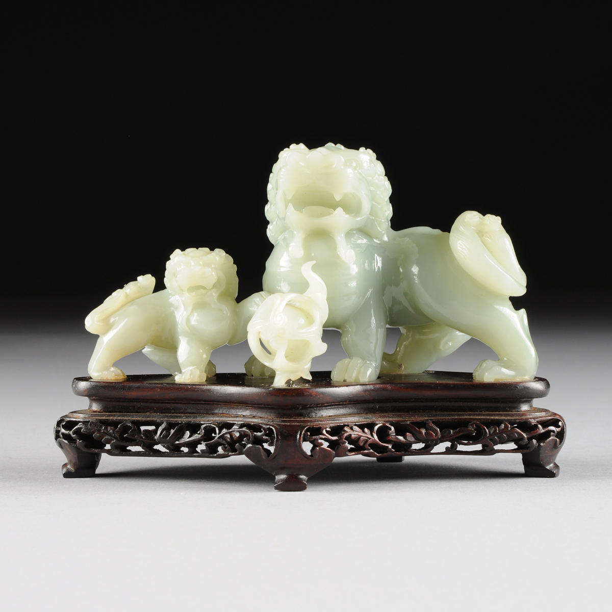 A CHINESE CARVED JADEITE FIGURAL GROUP OF TWO FOO DOGS, 20TH CENTURY, of a large foo dog with a