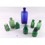 A group of seven green small bottles and one blue