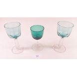 Two green wine glasses with pillar stems and one other with facet cut stem