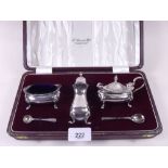 A silver three piece cruet set with liners and two spoons - all cased