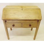 A Victorian pine desk with slope front over two drawers