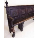 A 19th century long continental settle with five panel back carved grotesque masks with scroll arms,
