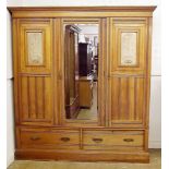 A Victorian triple satinwood wardrobe inset carved limewood panels of maidens flanking mirror door