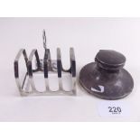 A small silver toast rack and a silver capstan inkwell